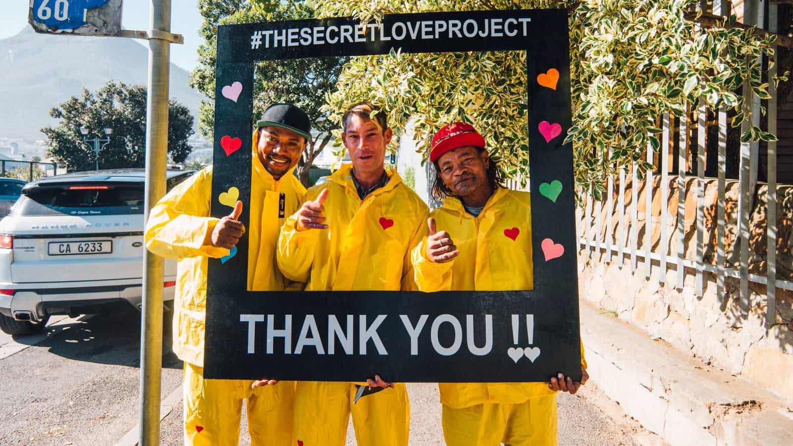 Three delighted sticker sellers in their donated rain suits from the Secret Love Project